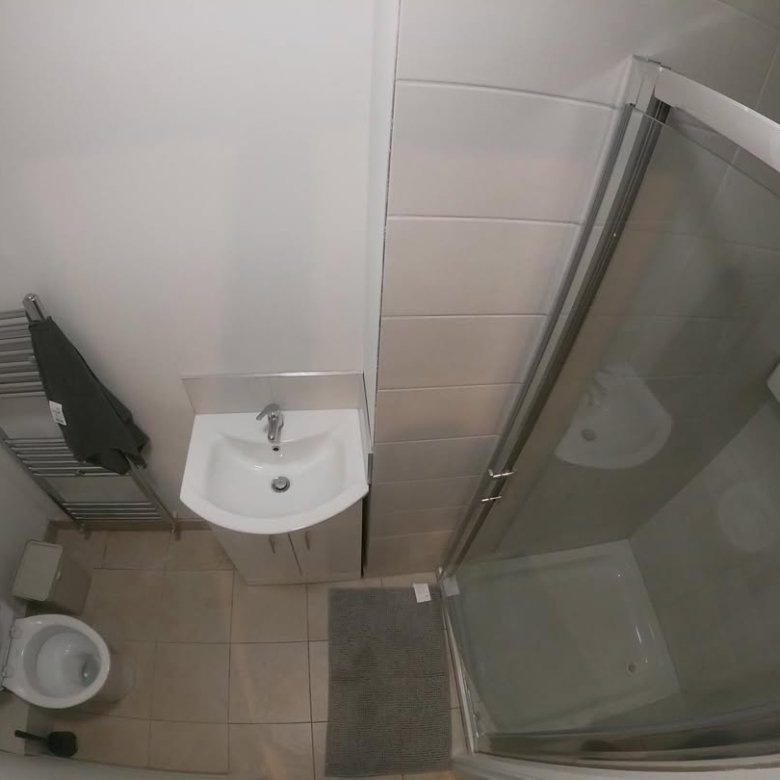 Small bathroom with toilet, sink, towel rack, and shower enclosure. Clean and functional design.