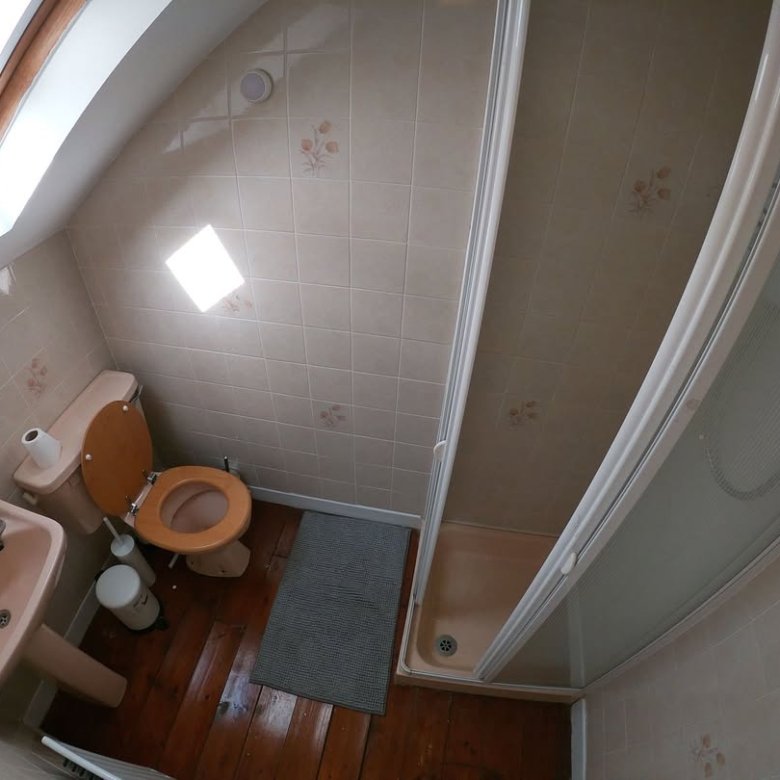 Small bathroom with toilet, sink, and shower in a compact space.