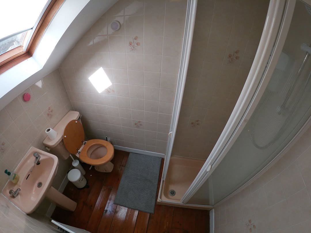 Small bathroom with toilet, sink, and shower in a compact space.