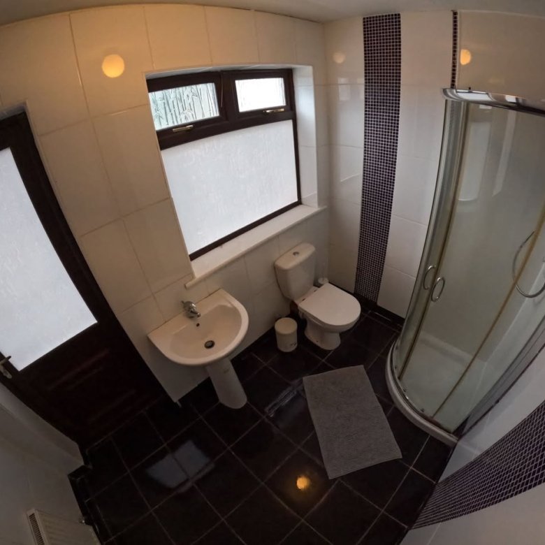 Small bathroom with toilet, sink, and shower stall, dark tile floor.