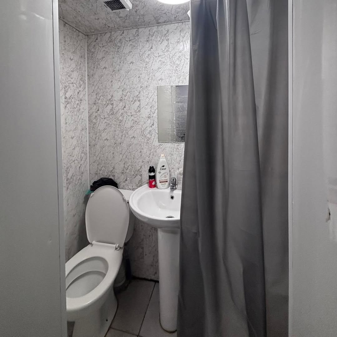 Small bathroom with toilet, sink, and shower curtain.