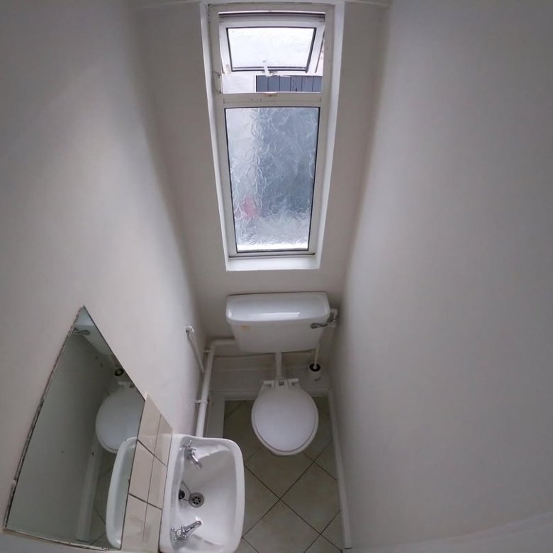 Small bathroom with toilet, sink, mirror, and a skylight window.