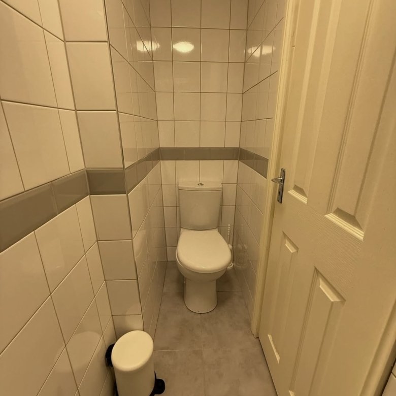 Small bathroom with toilet, tiled walls, and a white door.