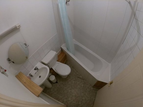 Small bathroom with tub, toilet, sink, and shower curtain.