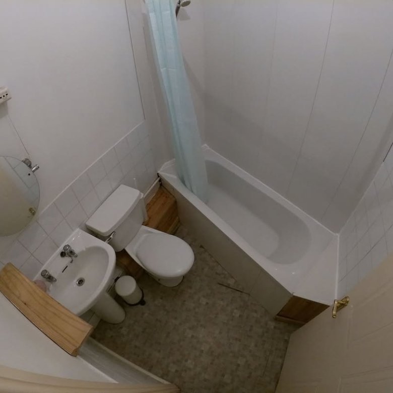 Small bathroom with tub, toilet, sink, and shower curtain.