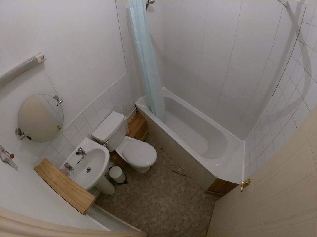 Small bathroom with tub, toilet, sink, and shower curtain.