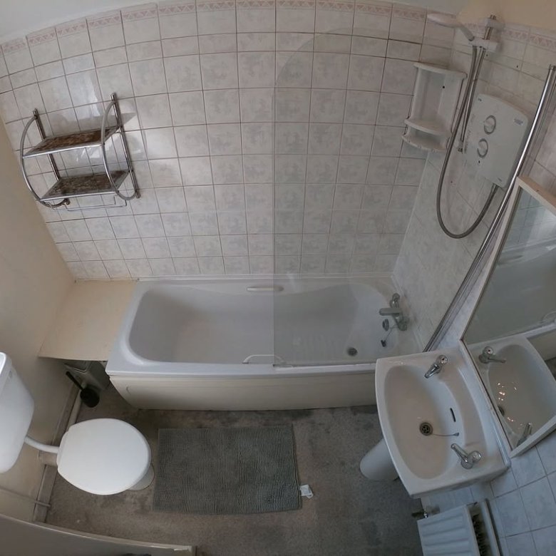 Small bathroom with tub, toilet, sink, and tiled walls. Interior design.