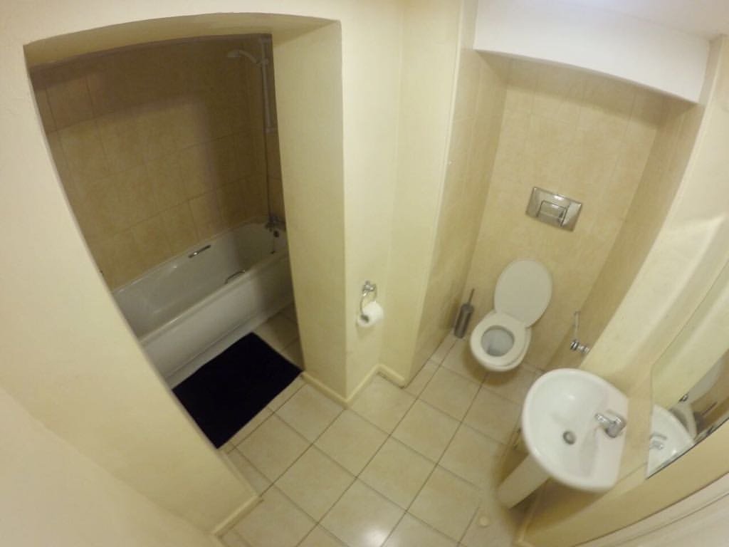 Small bathroom with tub, toilet, and sink in a compact space.