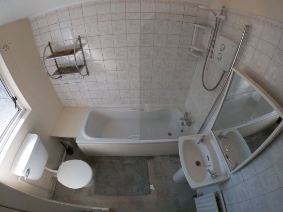 Bathroom with white fixtures, tub, toilet, sink, and tiled walls.