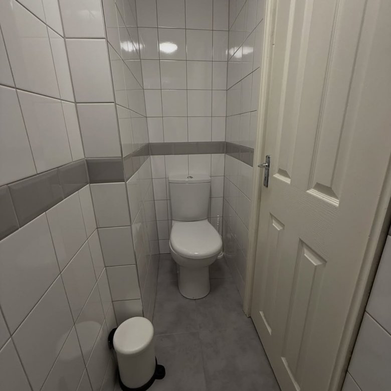Small bathroom with white toilet, tiled walls, and gray trim.