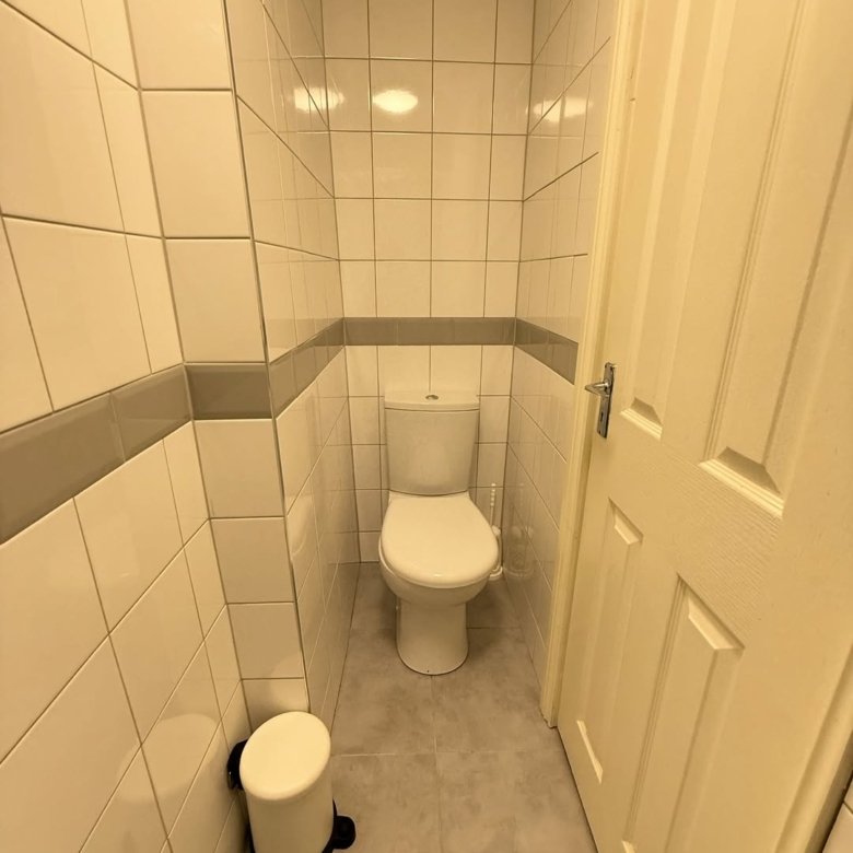 Small bathroom with white toilet, tiled walls, and gray accent stripe.