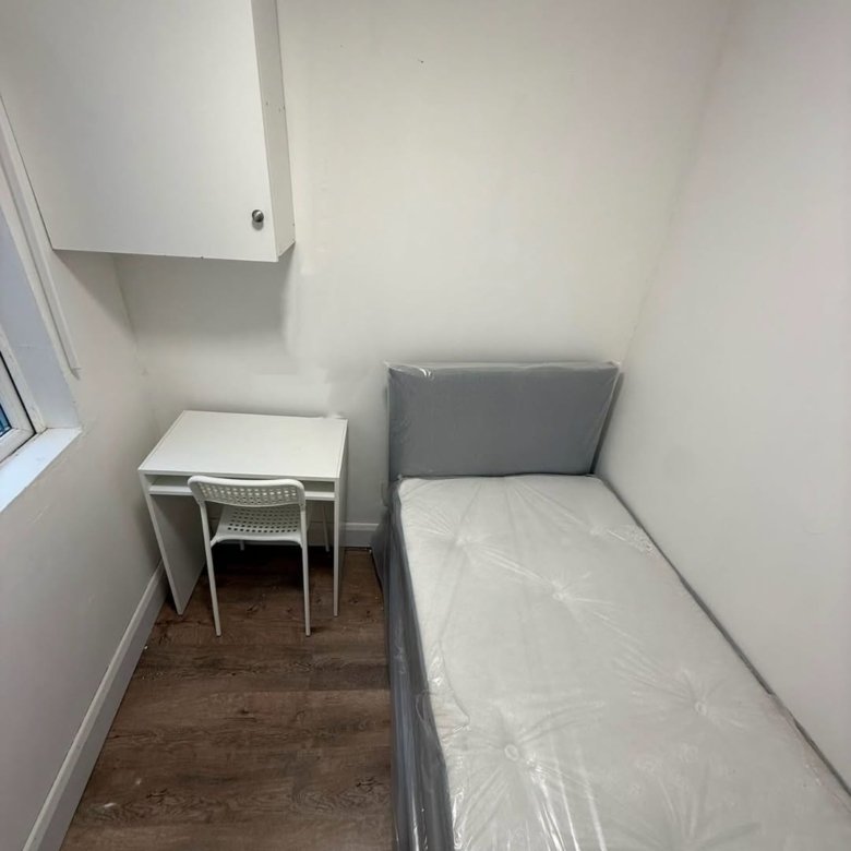 Small bedroom with single bed, desk, and wall cabinet. Minimalist interior.