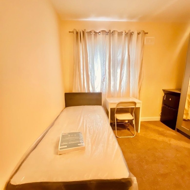 Small bedroom with single bed, desk, chair, and wardrobe. Neutral colors, minimalist style.