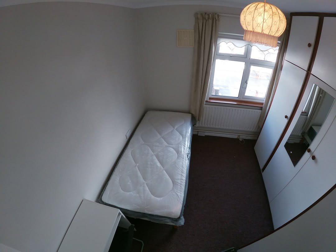 Small bedroom with single bed, wardrobe, desk, and window.