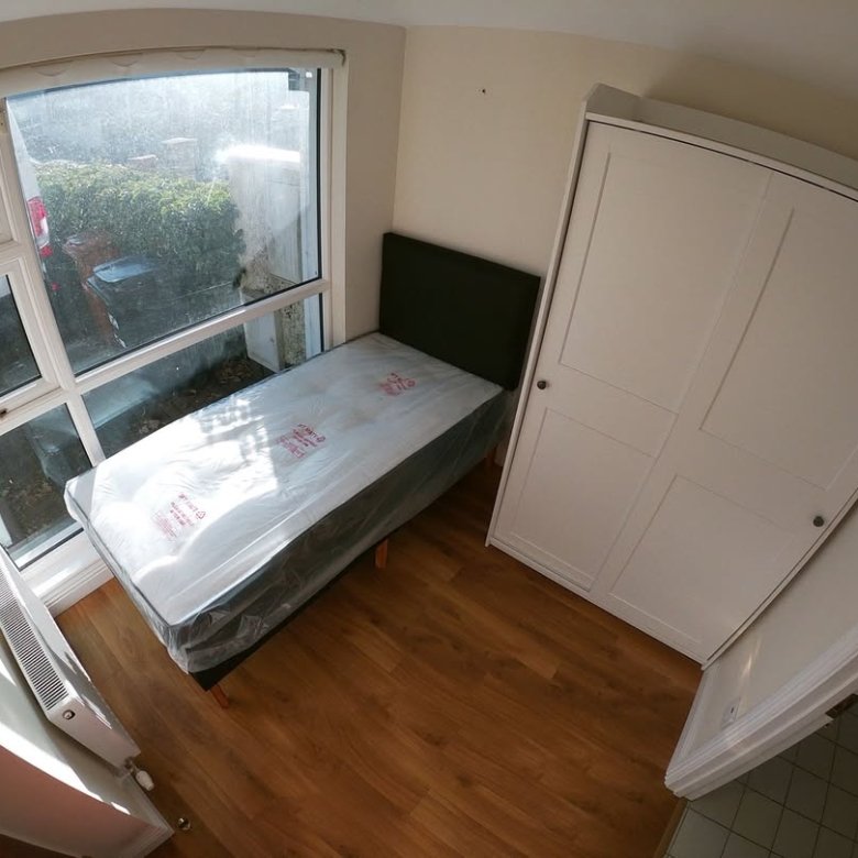 Small bedroom with single bed, wardrobe, and window. Natural light.