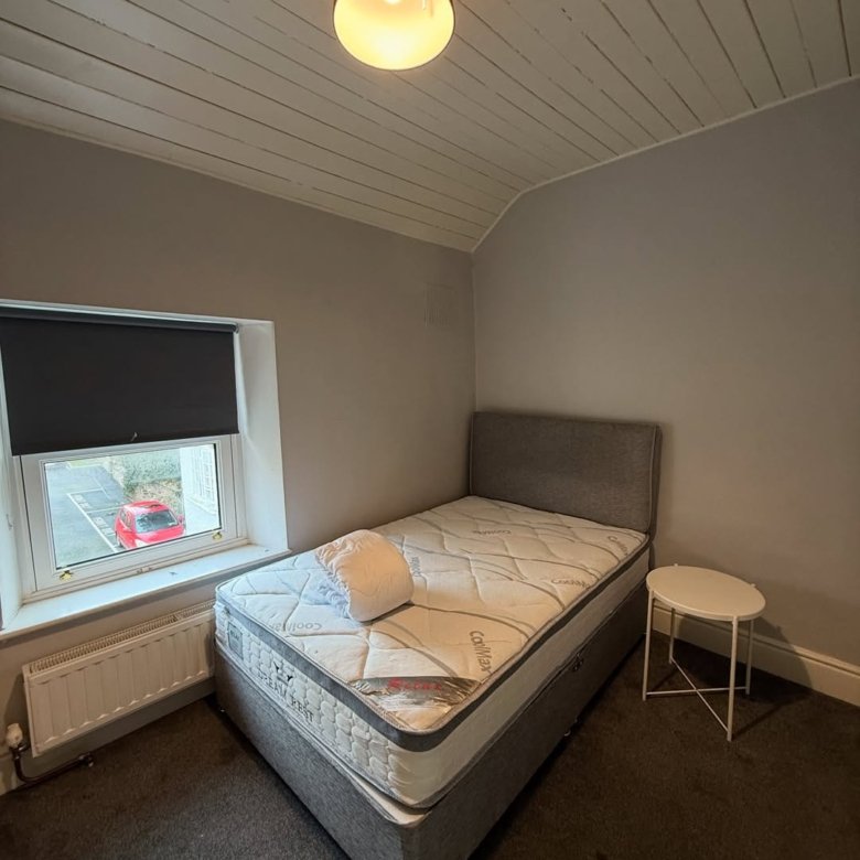 Cozy bedroom with single bed, window, and small side table.