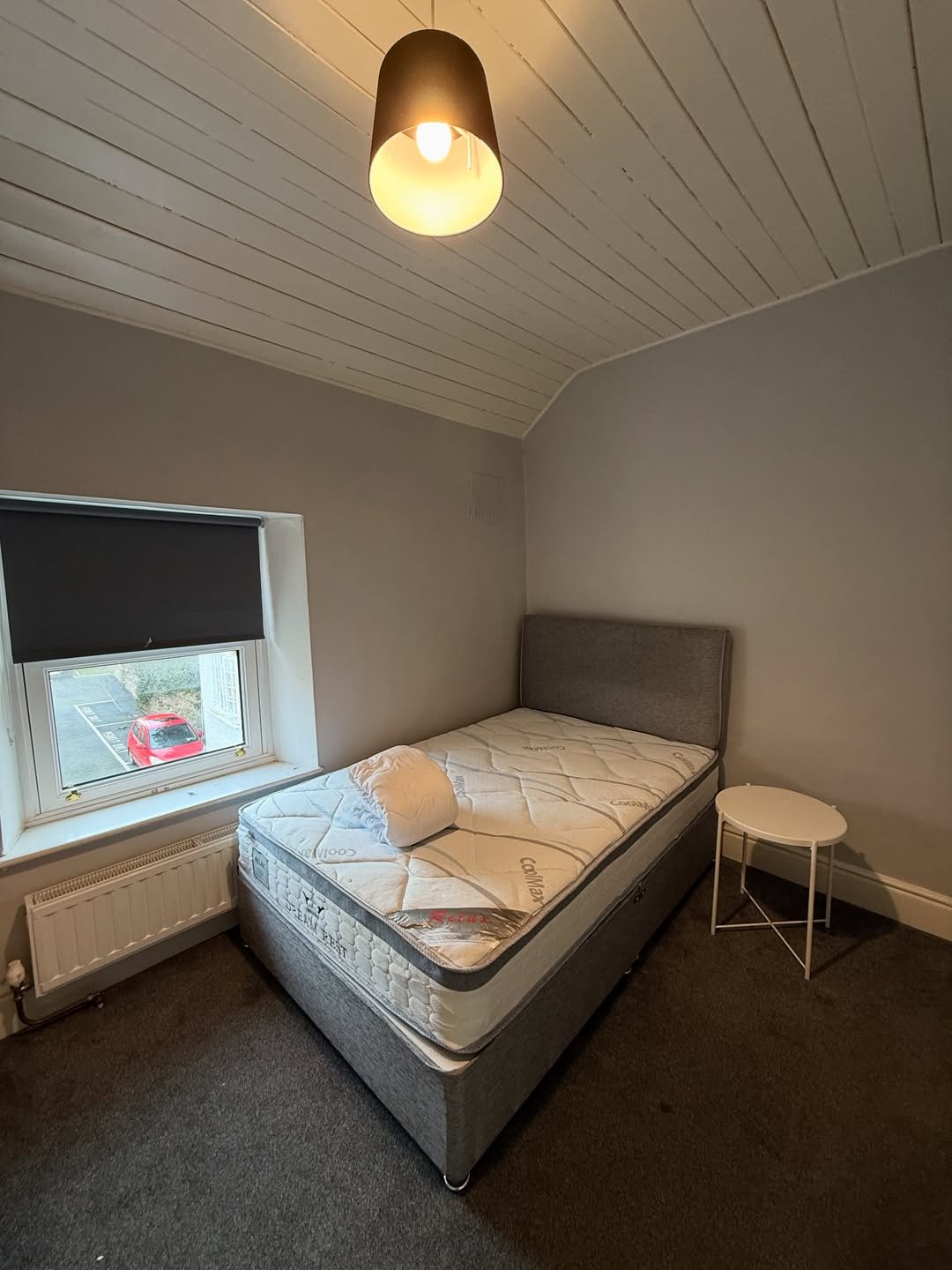 Cozy bedroom with single bed, window, and small side table.