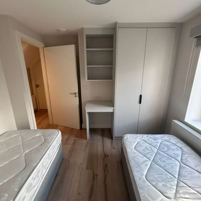 Small bedroom with two single beds, built-in wardrobe, and desk.