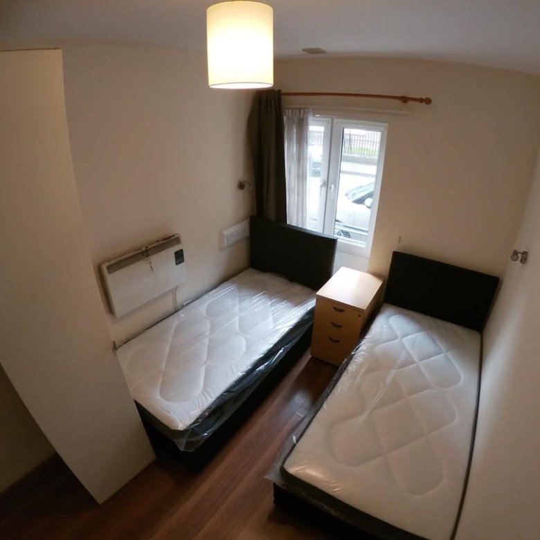 Small bedroom with two twin beds and a bedside table between them.