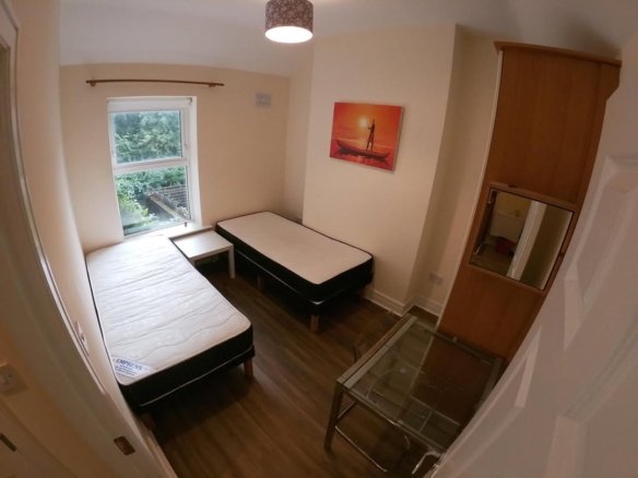 Cozy bedroom with two beds, desk, mirror, and artwork.
