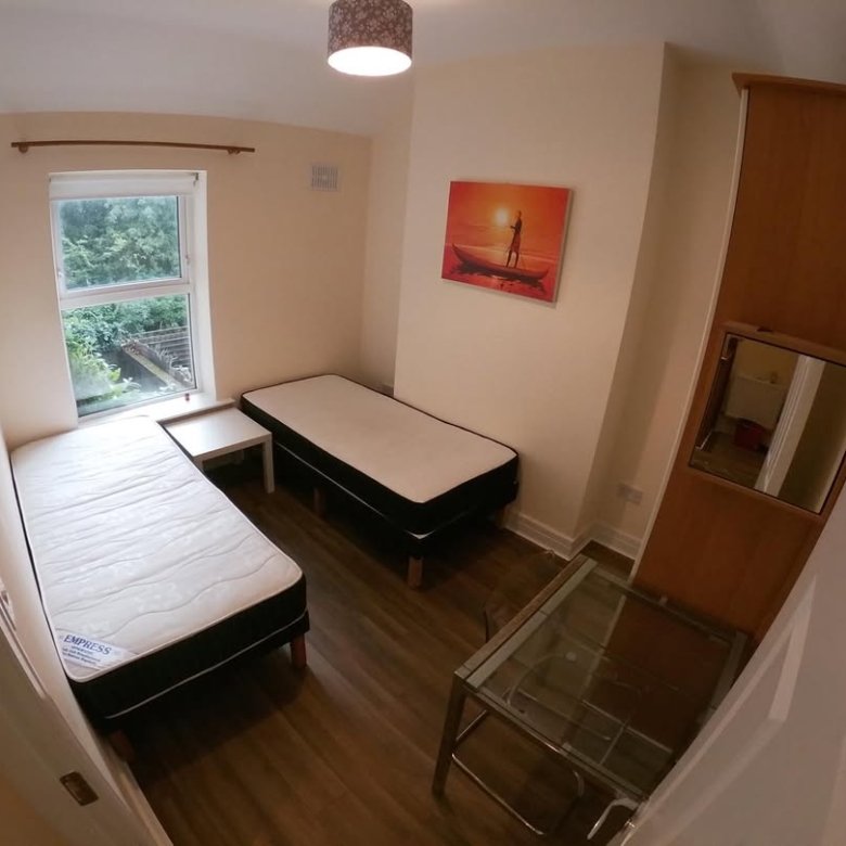 Cozy bedroom with two beds, desk, mirror, and artwork.