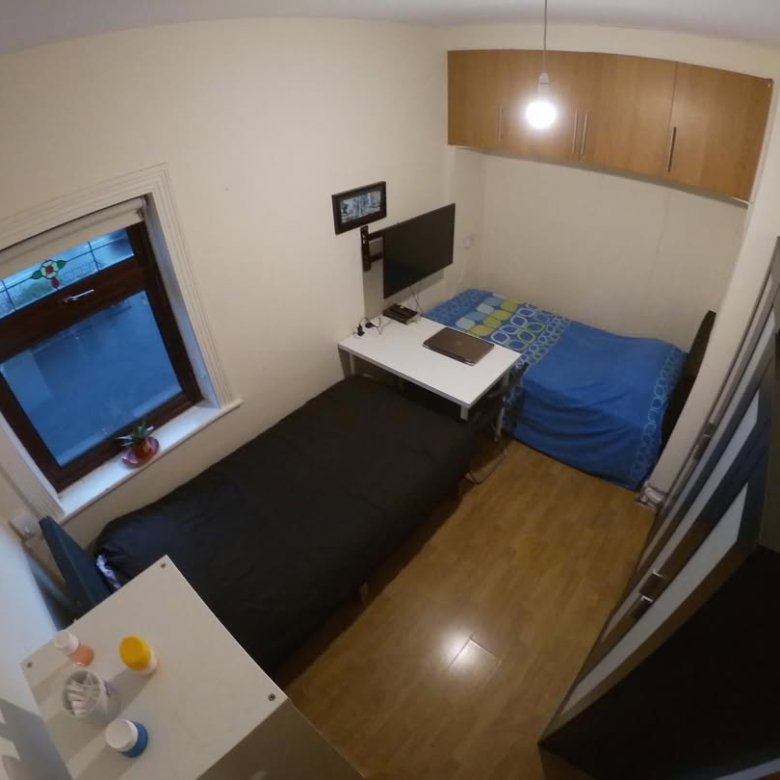 Small bedroom with two beds, desk, and storage cabinets. Compact living space.