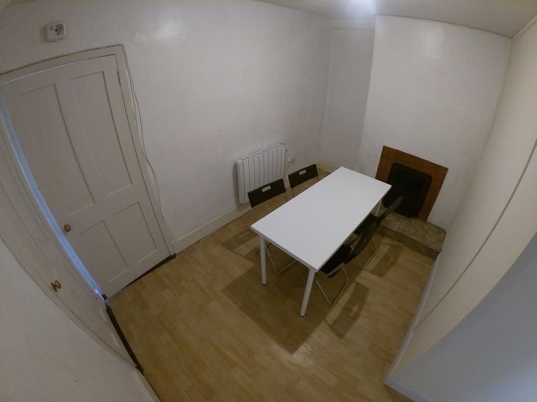 Small dining room with white table, black chairs, and a fireplace.