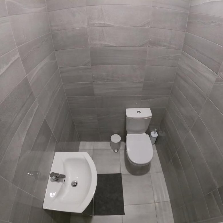 Small bathroom with gray tile, toilet, and sink. Modern design.