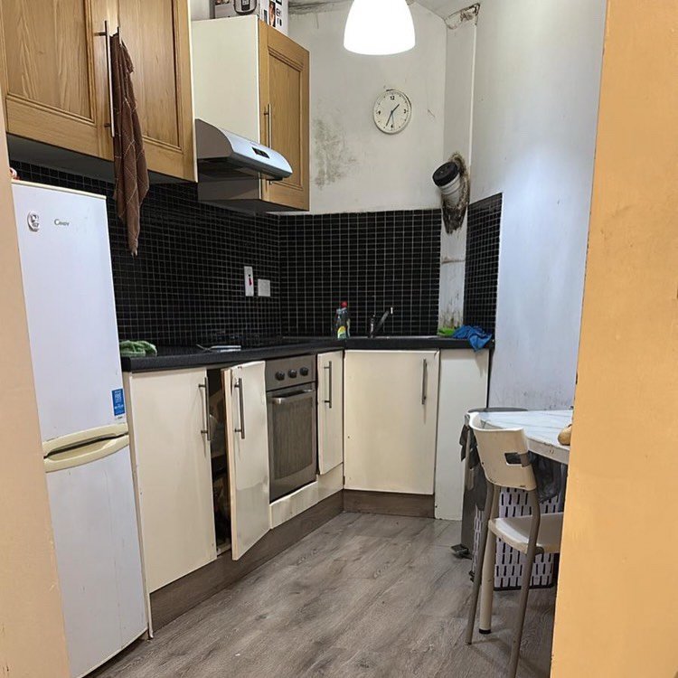 Small kitchen with white cabinets, black backsplash, and gray flooring.