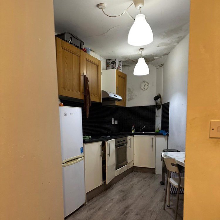Small kitchen with white cabinets, appliances, and gray flooring.