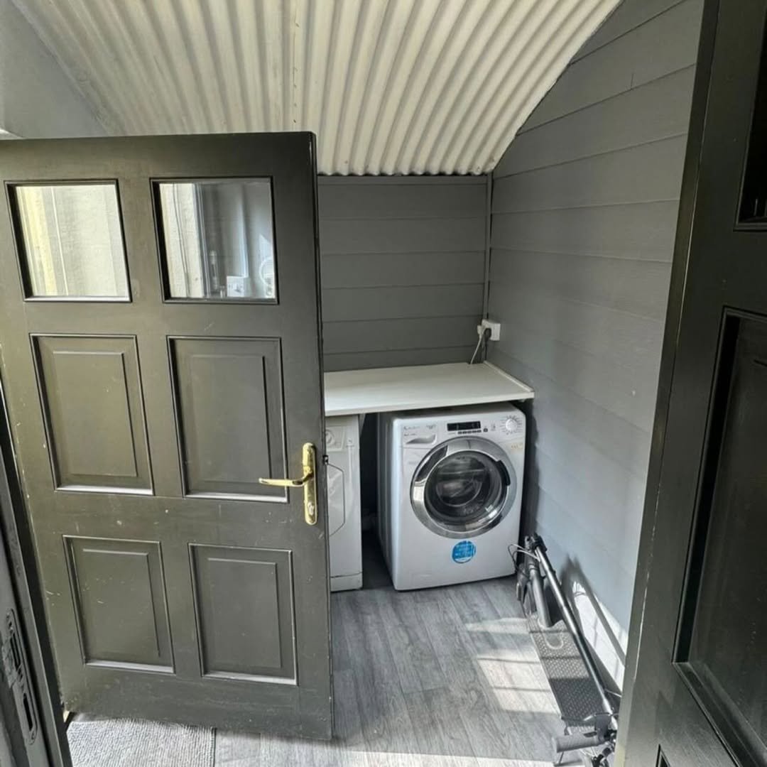 Laundry room with washing machine, gray walls, and black door.