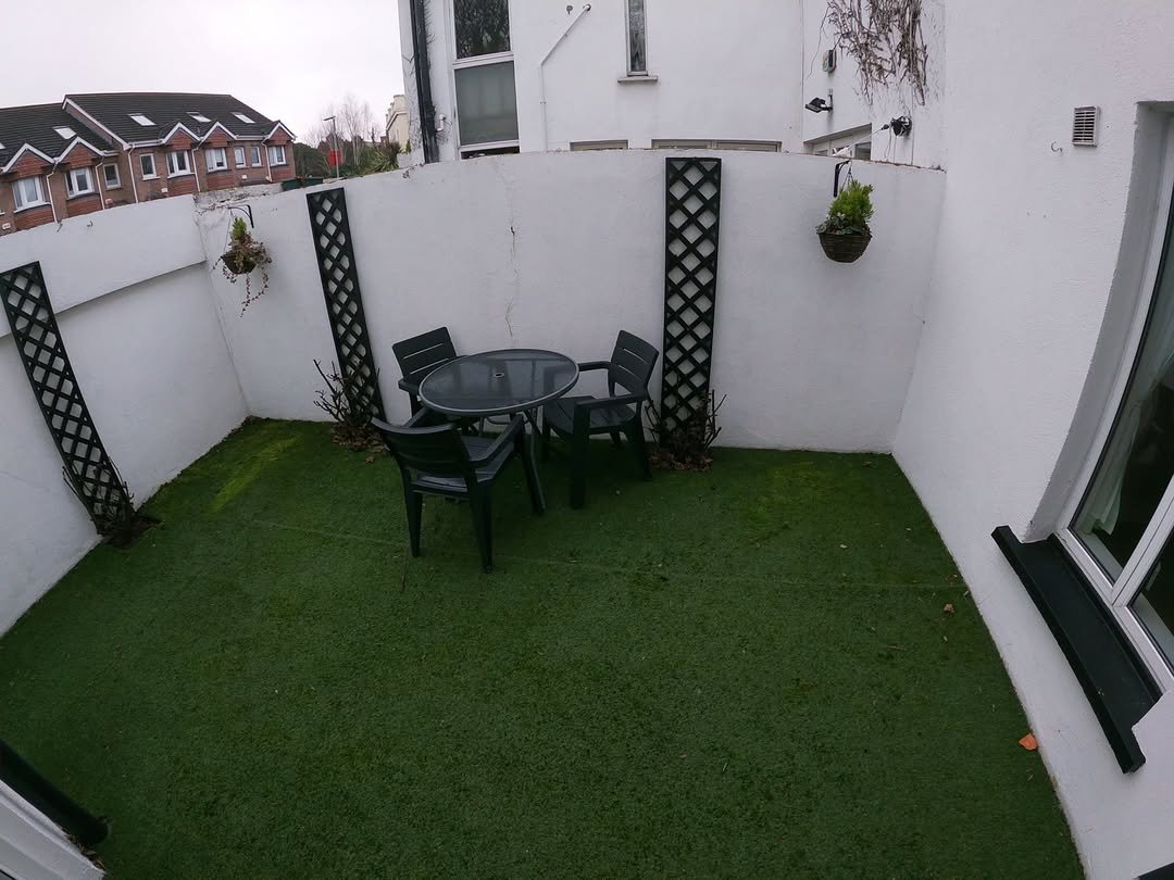 Small outdoor patio with artificial grass, table, and chairs.