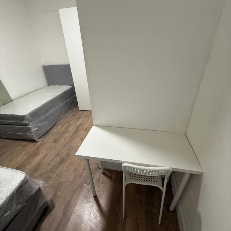 Small room with beds and desk, minimalist white furniture.