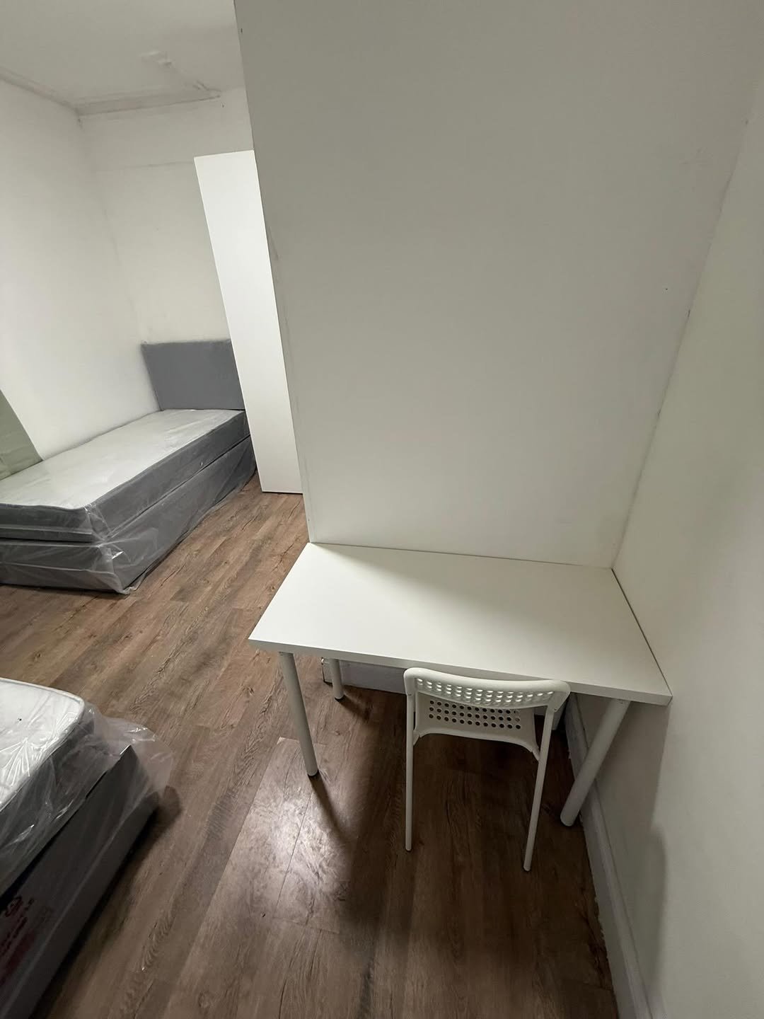 Small room with beds and desk, minimalist white furniture.