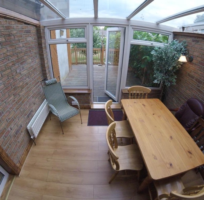 Sunroom with brick walls, wooden table, chairs, and view to outdoor patio.