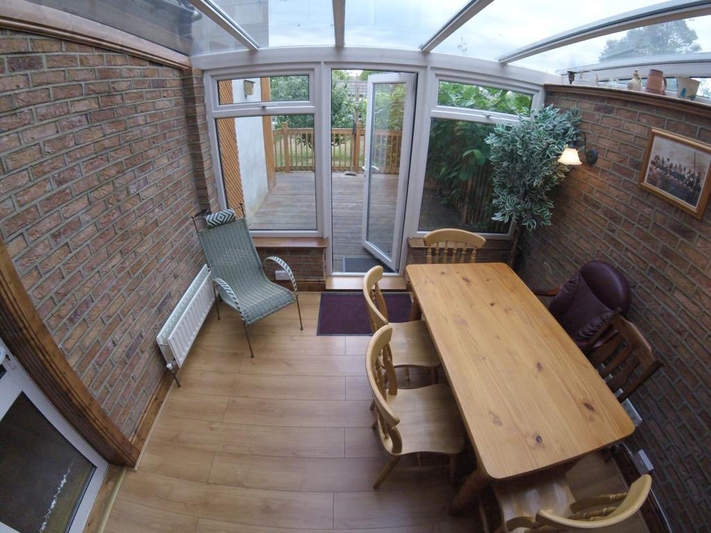 Sunroom dining area with brick walls, wood table, and chairs.