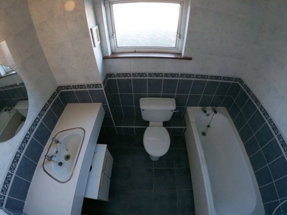 Overhead view of a tiled bathroom with toilet, sink, and bathtub.