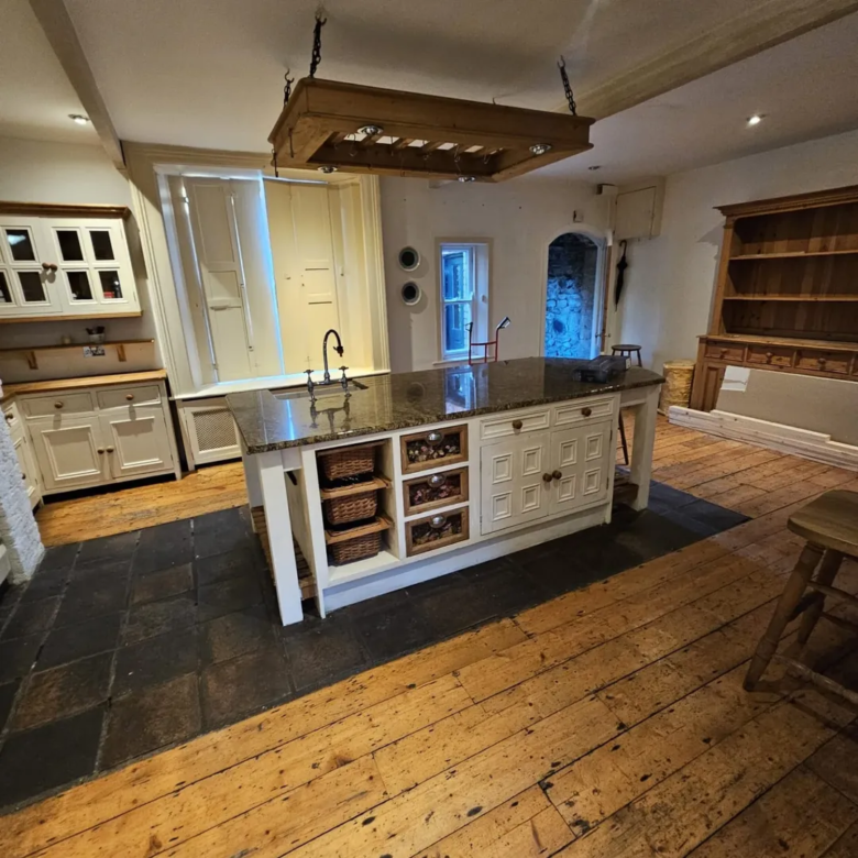 Traditional kitchen with island, wooden floors, and rustic hanging light fixture.