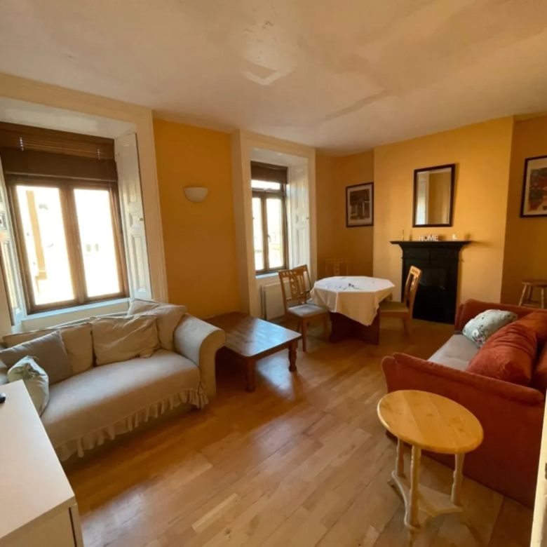 Cozy living room with sofas, dining table, and fireplace in warm tones.