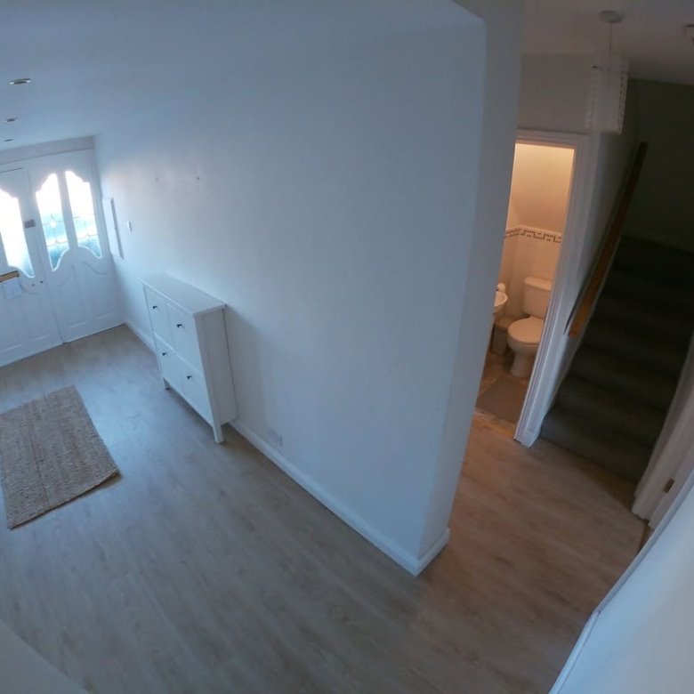 Entryway with white walls, wooden floors, stairs, and white cabinet.