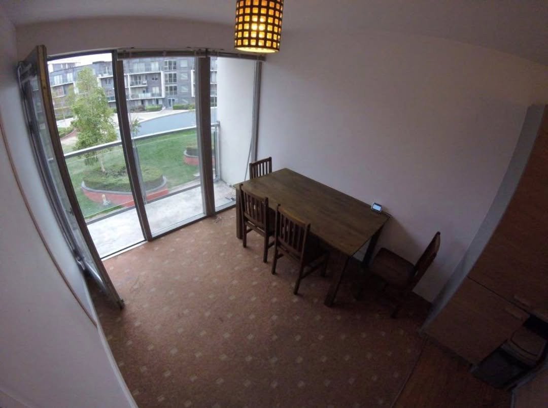 Apartment dining area with table, chairs, and balcony view.