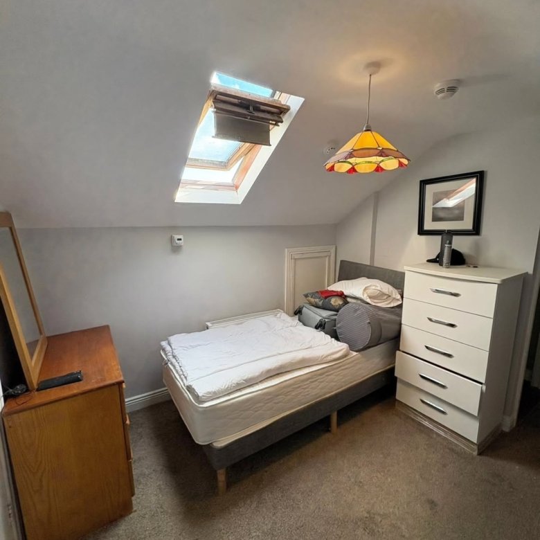 Attic bedroom with bed, skylight, dresser, and chest of drawers.