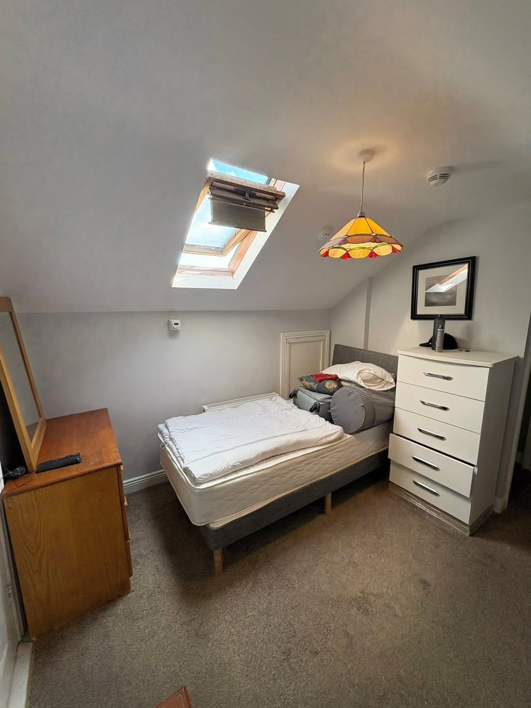 Attic bedroom with bed, skylight, dresser, and chest of drawers.