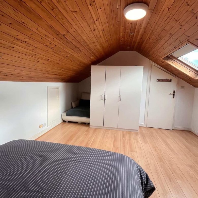 Attic bedroom with wood ceiling, wardrobe, and skylight. Cozy and bright space.