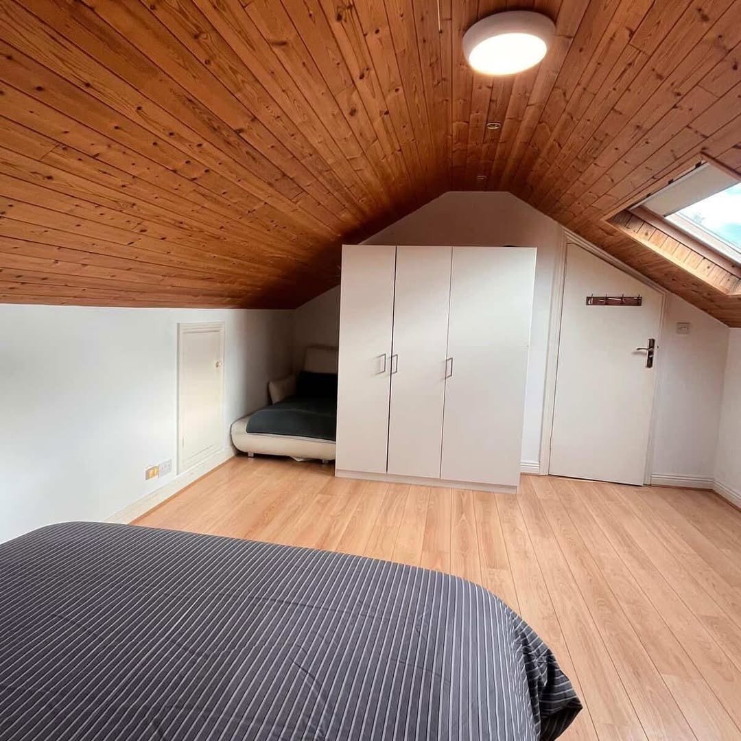 Attic bedroom with wood ceiling, wardrobe, and skylight. Cozy and bright space.