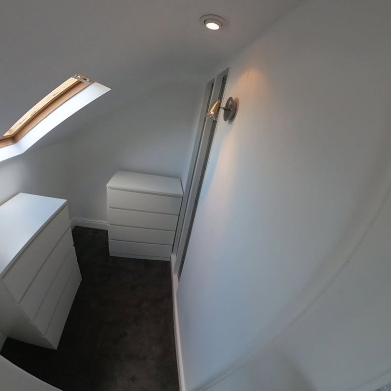 Attic room with skylight, fitted white drawers, and sloped ceiling.
