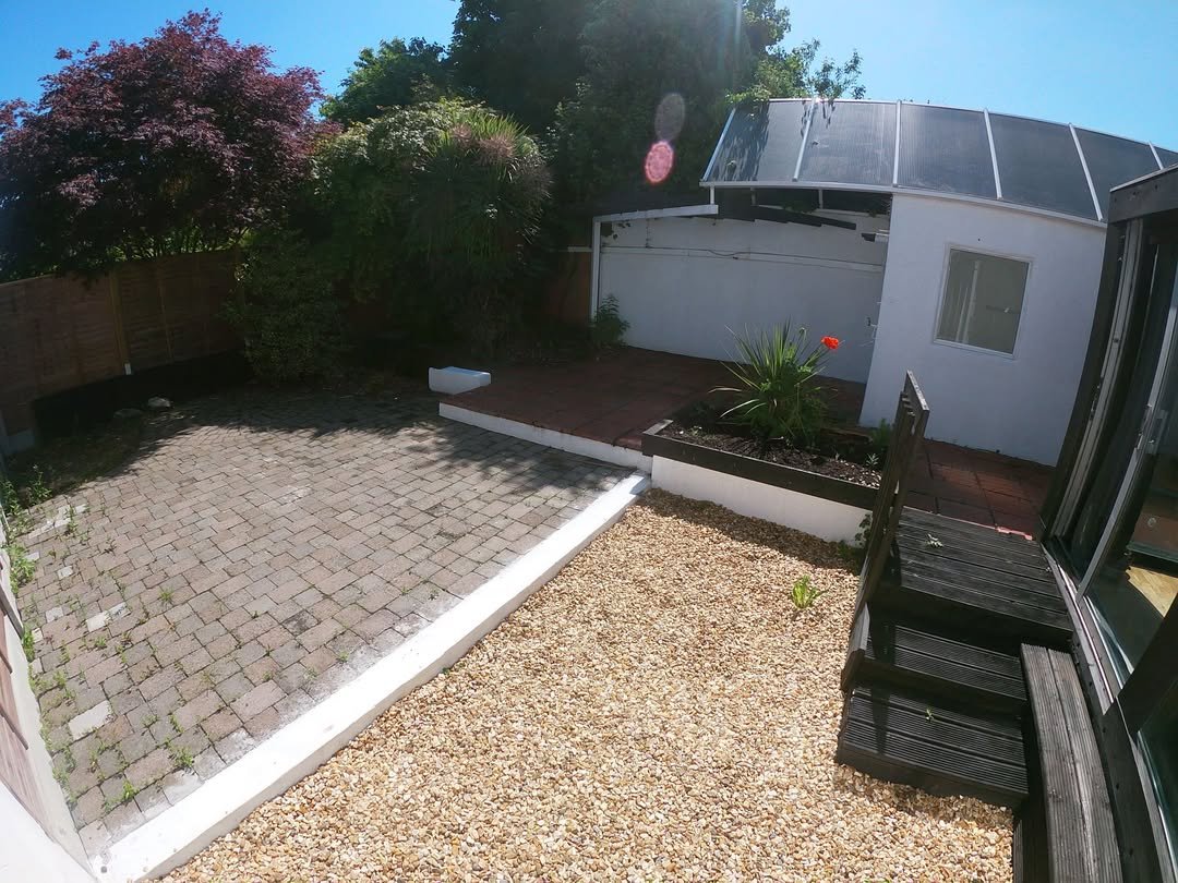 Backyard patio with brick paving, gravel area, and small garden bed.