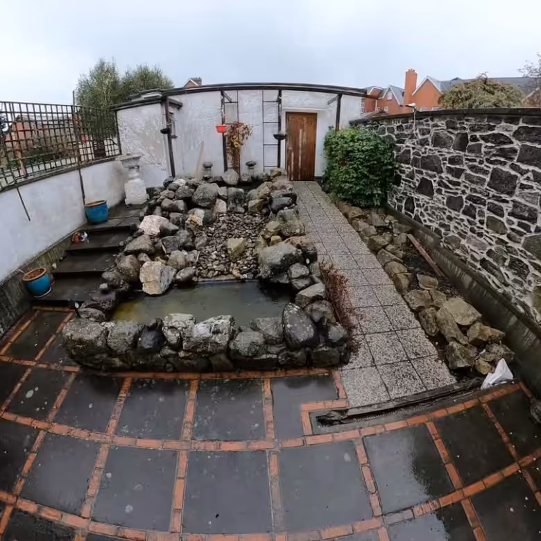Backyard pond with rock border and stone pathway in a garden setting.