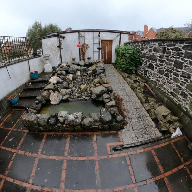 Backyard pond with rock border and stone pathway in a garden setting.