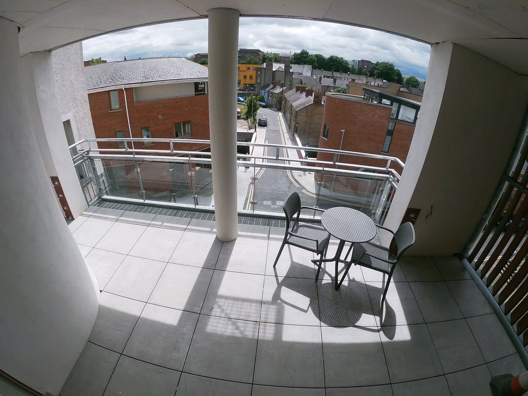 Balcony with table, chairs, and street view; residential building.